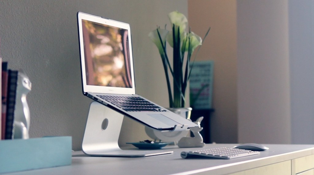 Bright desk detail with monitor stand, headphones and a clean work surface
